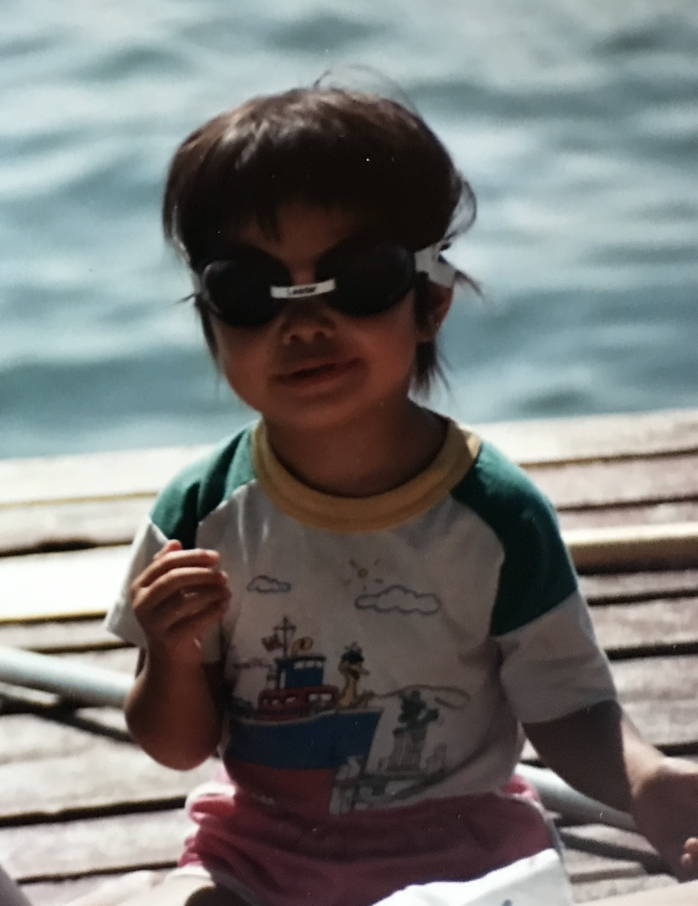 Adrienne as a child wearing swim goggles.